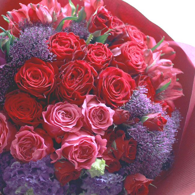 赤いバラ・赤いダリア・赤いチューリップ・ガマズミ・濃いピンクのアルストロメリアを使った花束の写真