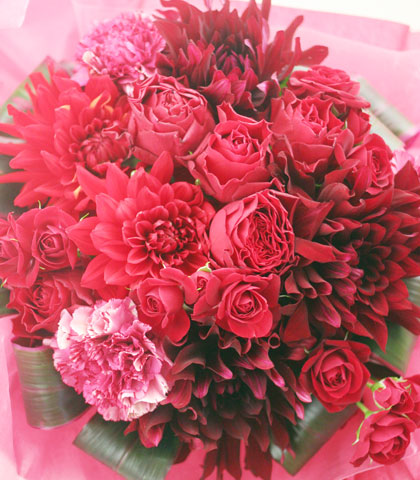 赤いバラ・赤いダリア・濃いピンクのカーネーション・ドラセナを使った花束の写真
