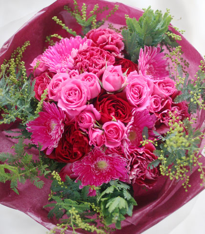 濃いピンクのバラ・濃いピンクのガーベラ・濃いピンクのカーネーション・ドラセナを使った花束の写真