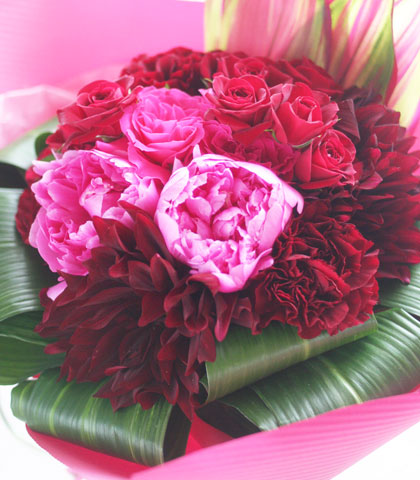 赤いバラ・ピンクのバラ・ピンクの芍薬・赤いダリア・ドラセナ・ハランを使った花束の写真